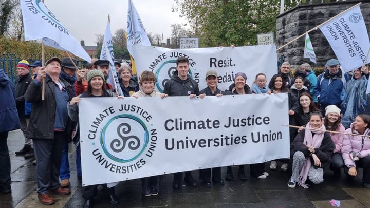 Photograph of CJUU members holding banners, flags and signs, at the start of the National Climate March